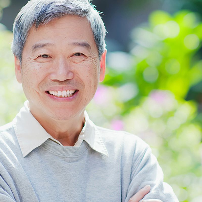 Smiling older man in a garden setting.