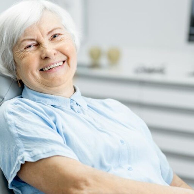 Smiling elderly woman in dentist chair.