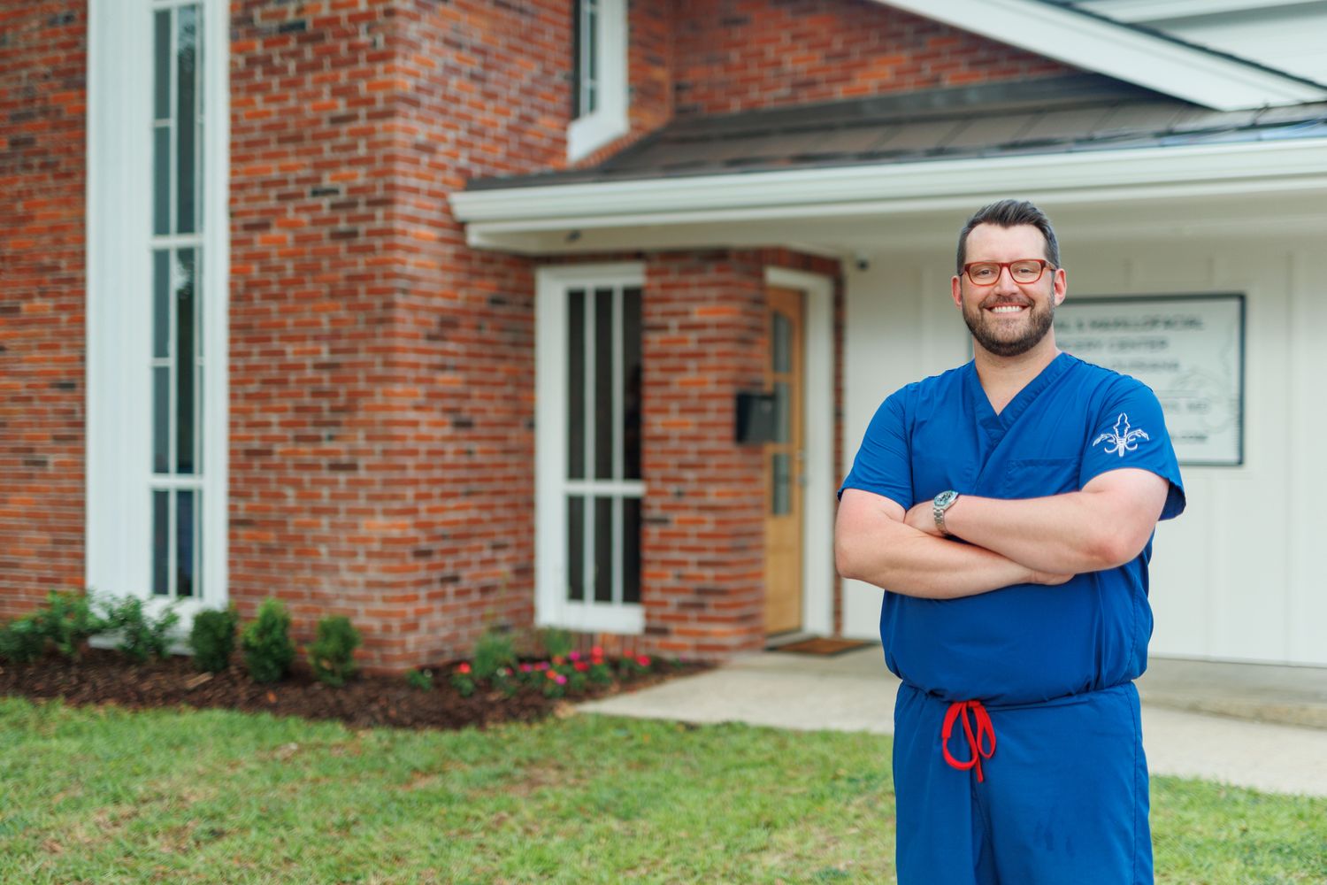 Man in blue scrubs outside building.