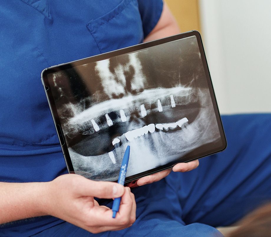 Dentist showing dental X-ray on tablet screen.