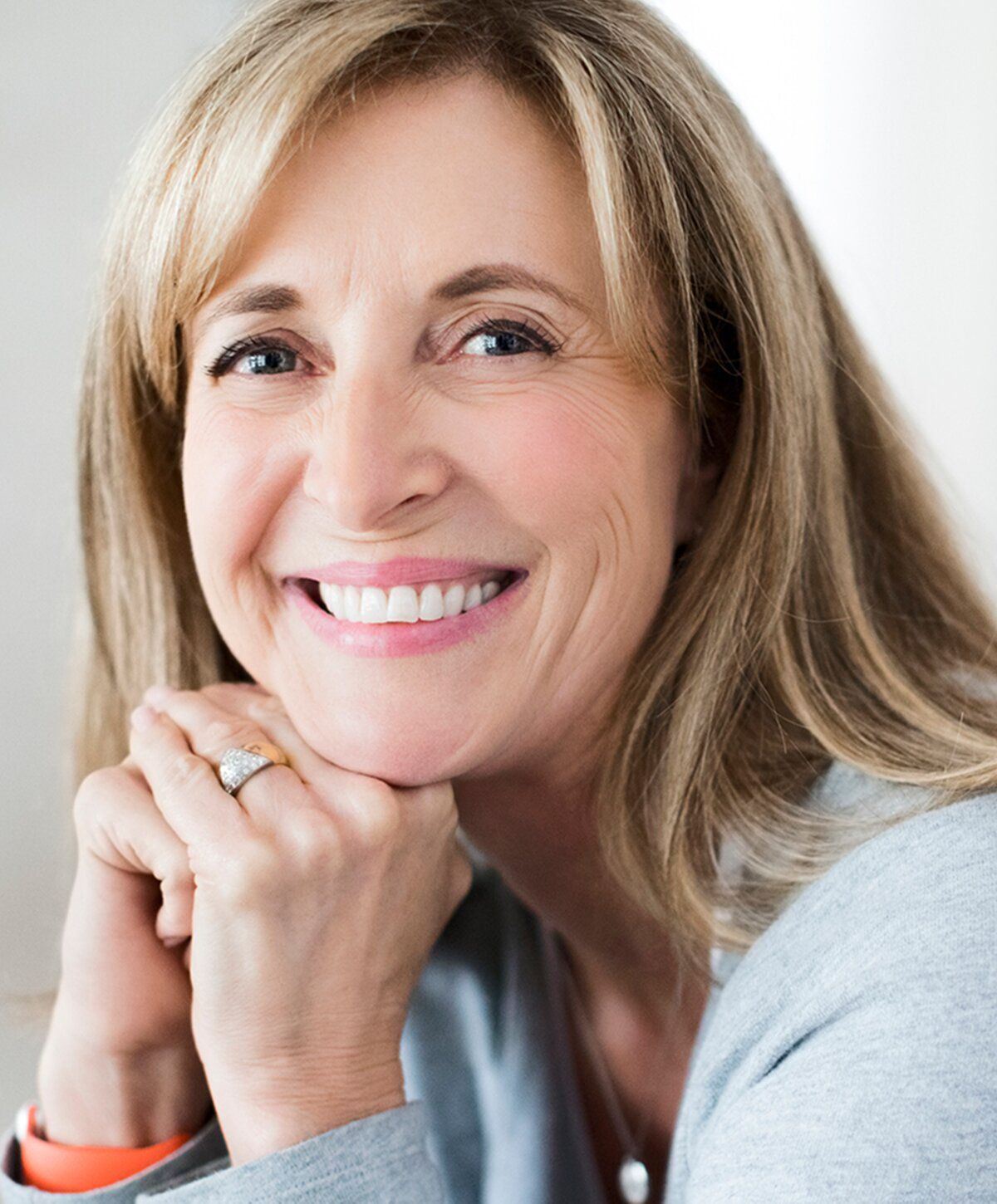 Smiling woman with long hair and hand resting.