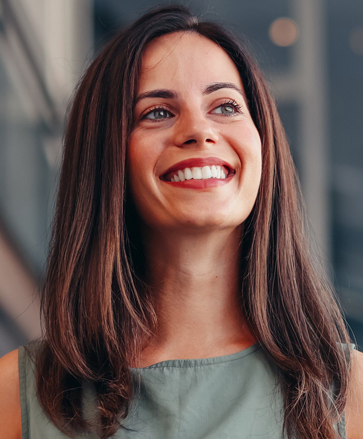 Smiling woman with long hair and green top.