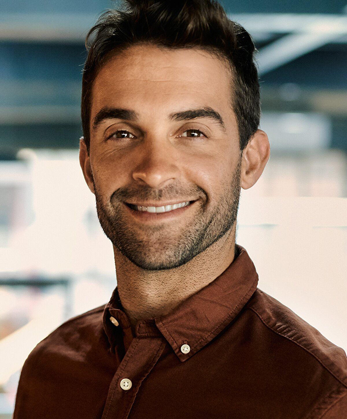 Smiling man in brown shirt against blurred background