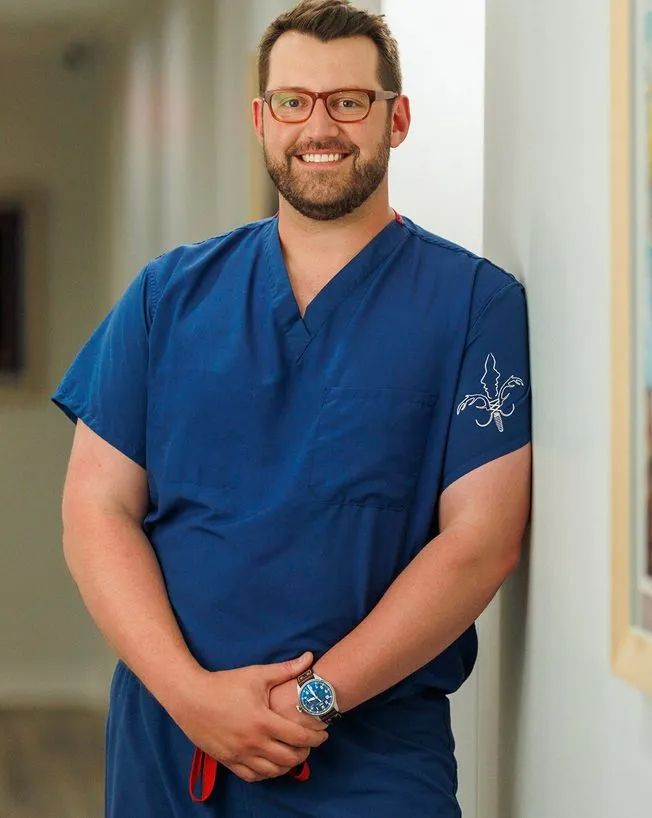 Smiling healthcare professional in blue scrubs.
