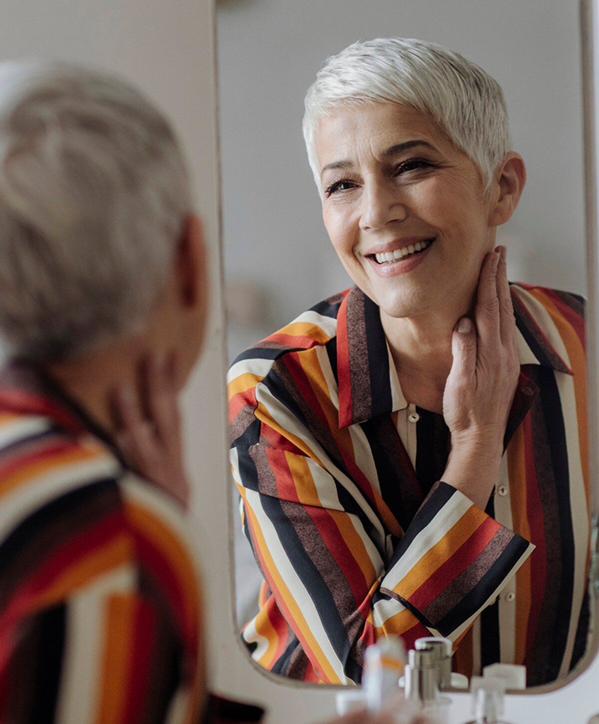 Smiling woman with short hair in mirror.