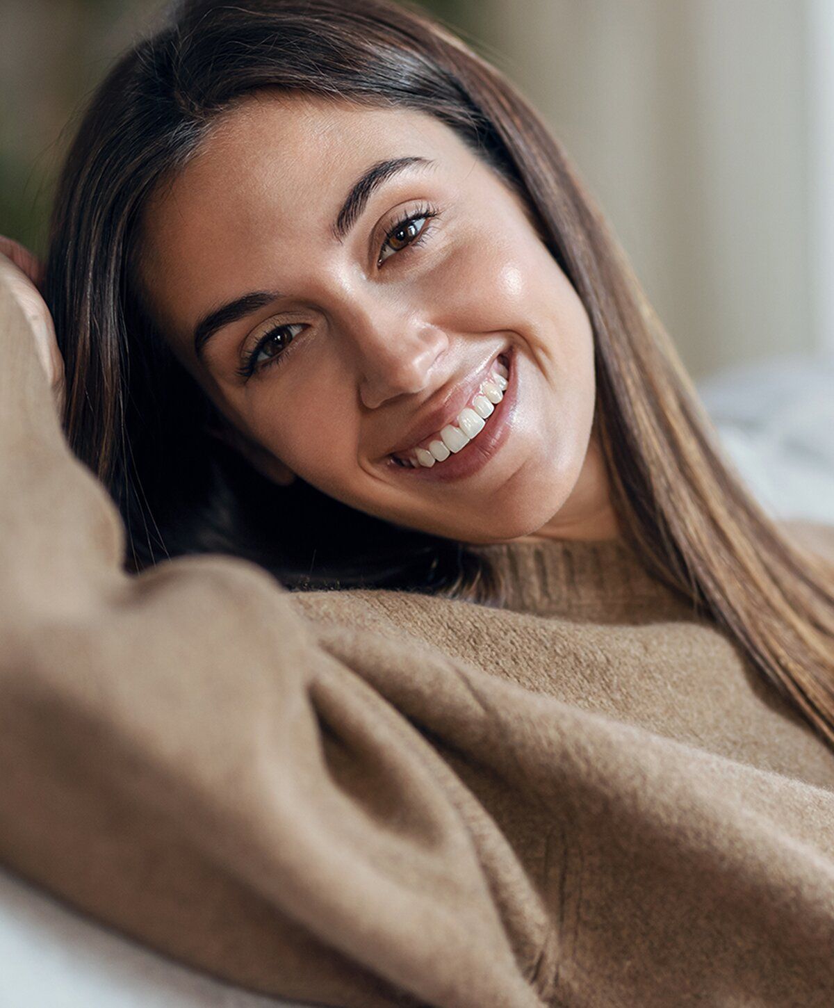 Smiling woman in cozy sweater, joyful expression.