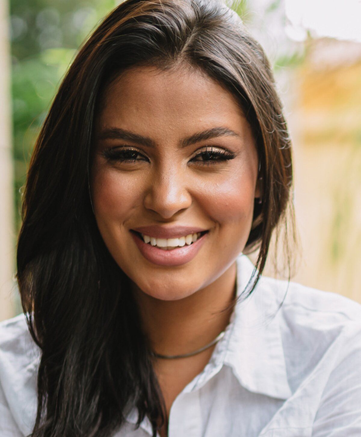 Smiling woman in casual white shirt outdoors.
