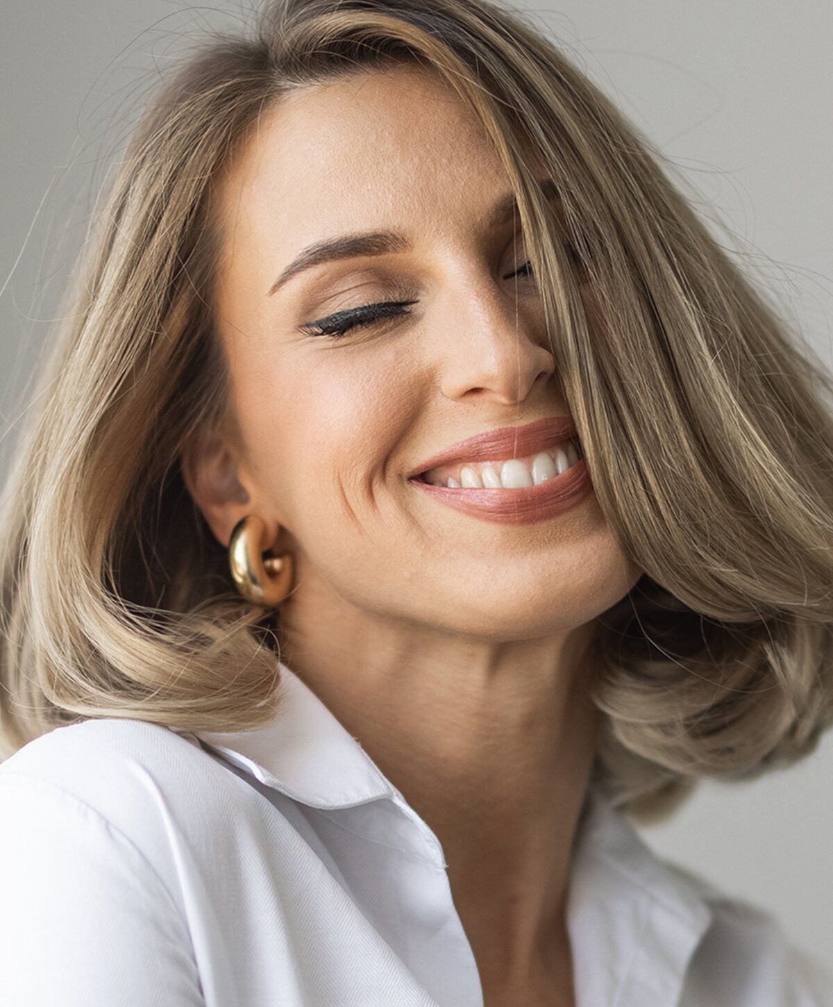 Smiling woman with blonde hair and earrings.