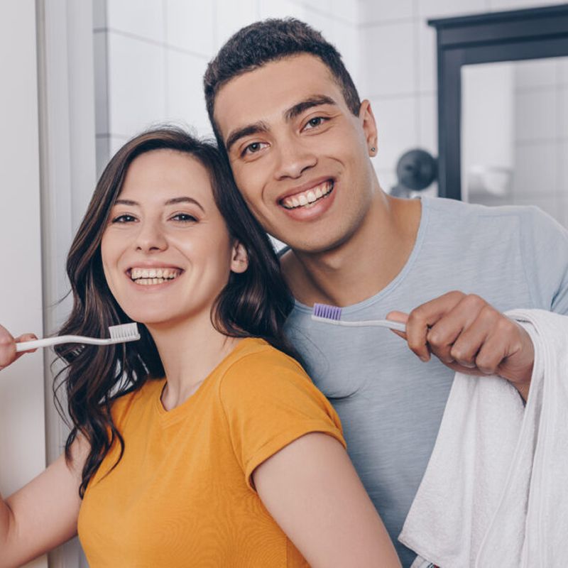 Happy couple brushing teeth in bathroom.