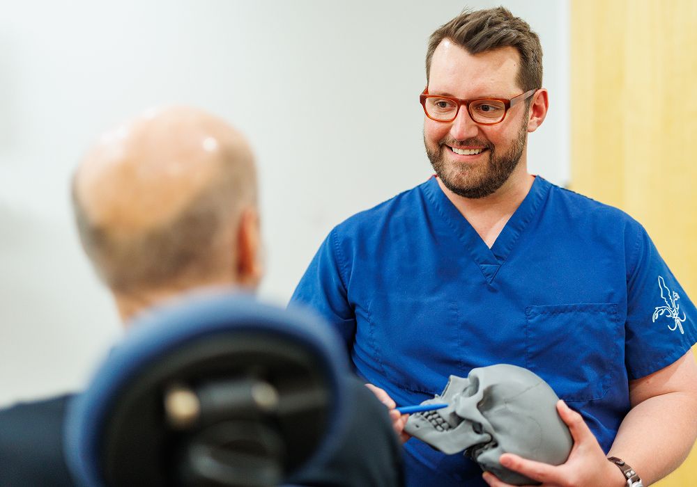 Medical professional discussing skull model with patient.