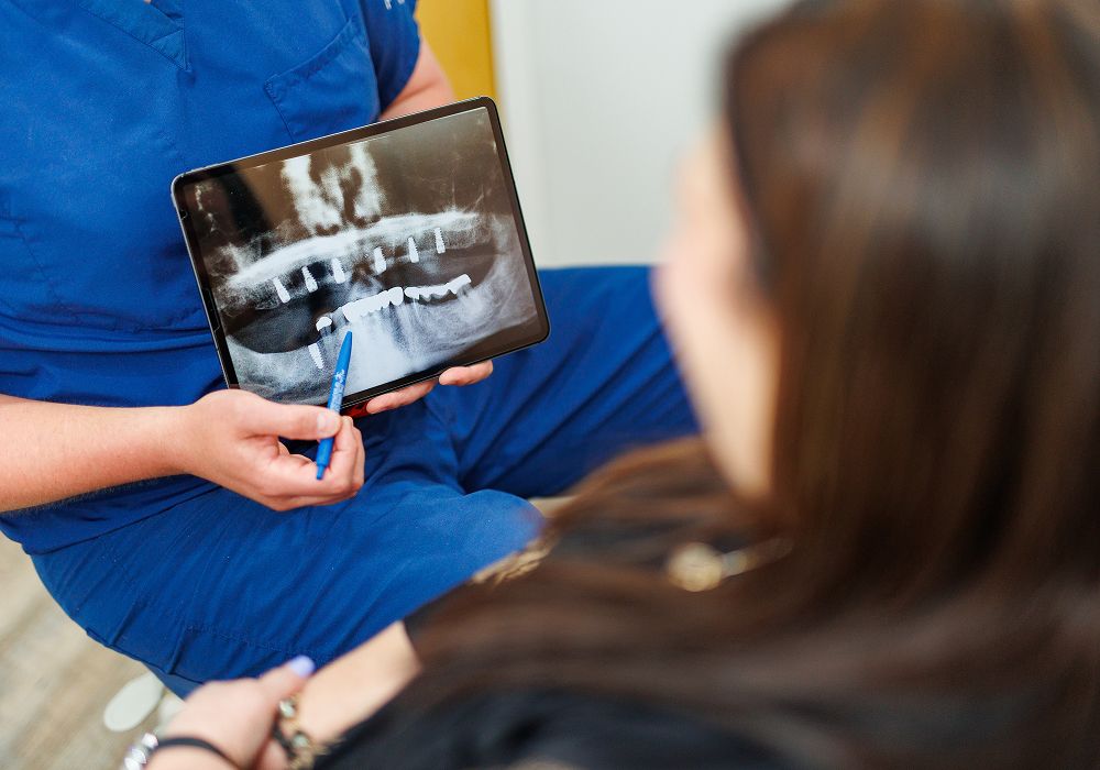 Dentist explaining X-ray to patient on tablet.