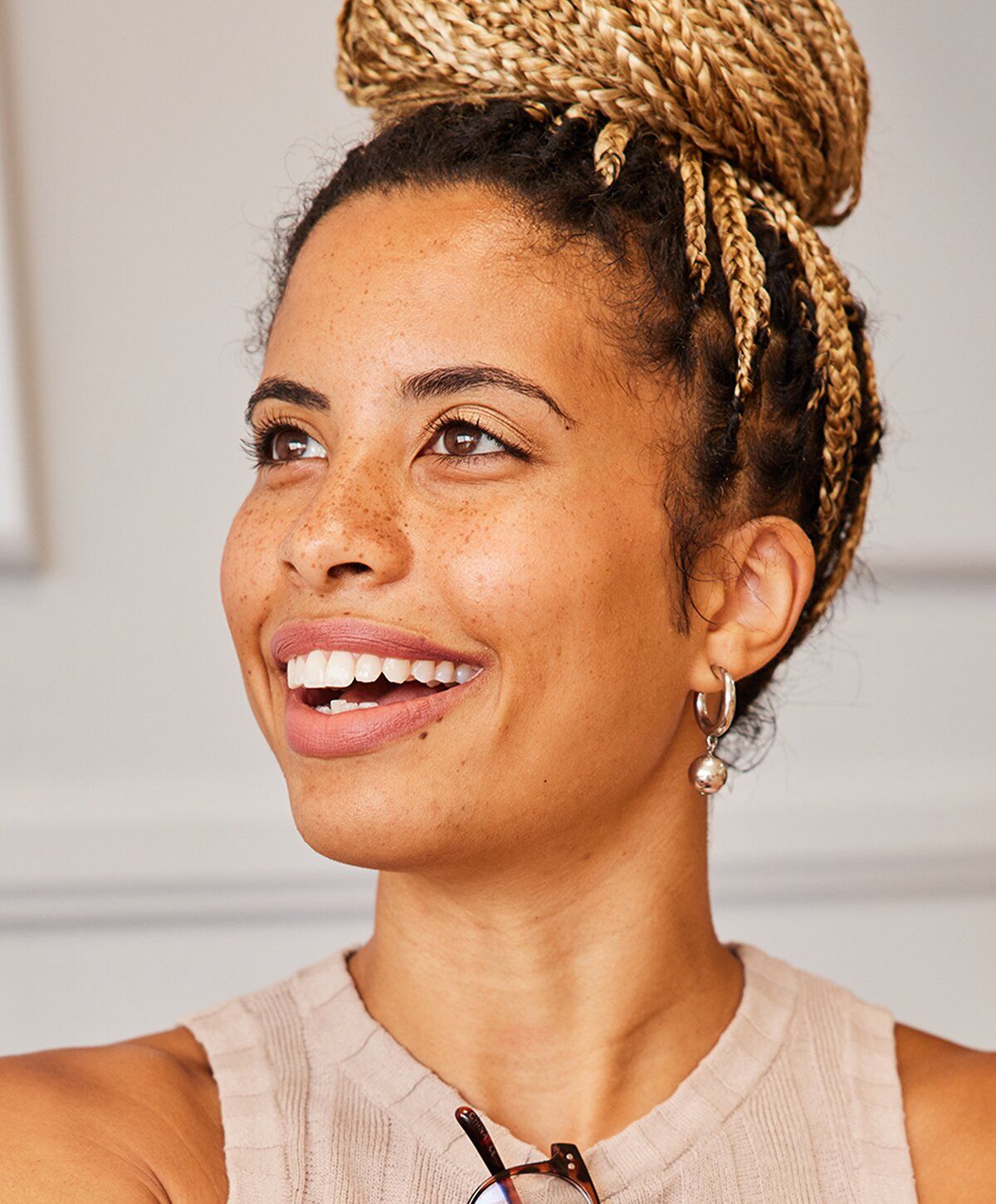 Smiling woman with braided hair and earrings.