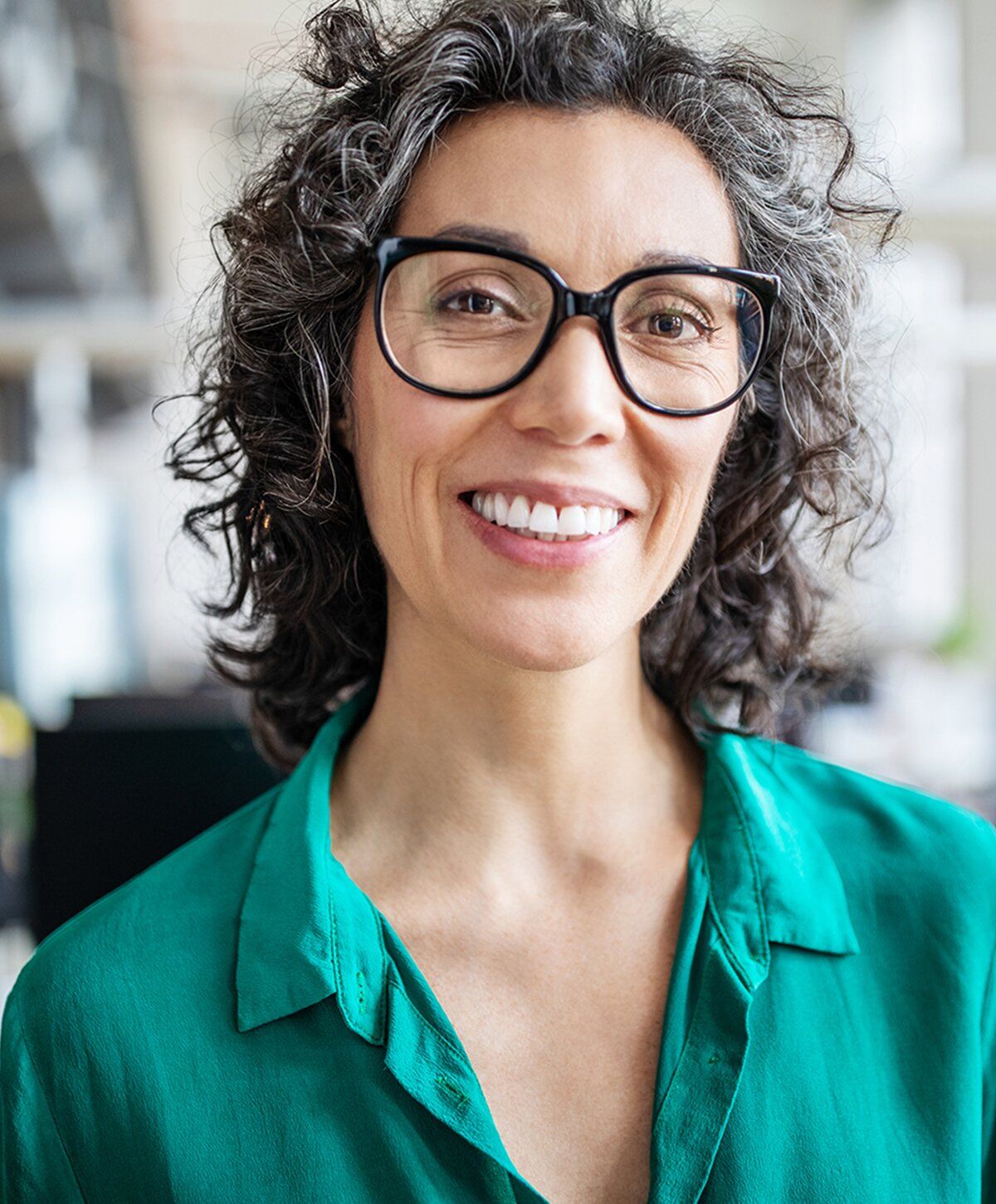 Smiling woman with curly hair and glasses.