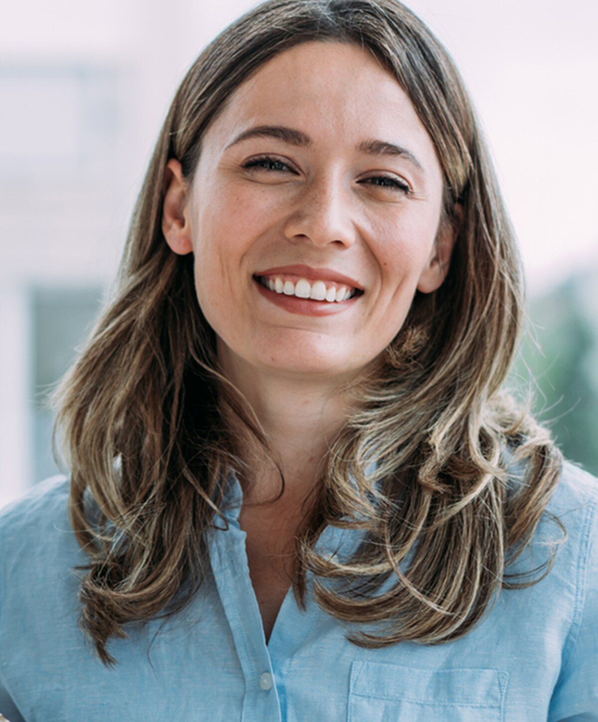 Smiling woman with long hair in blue shirt.