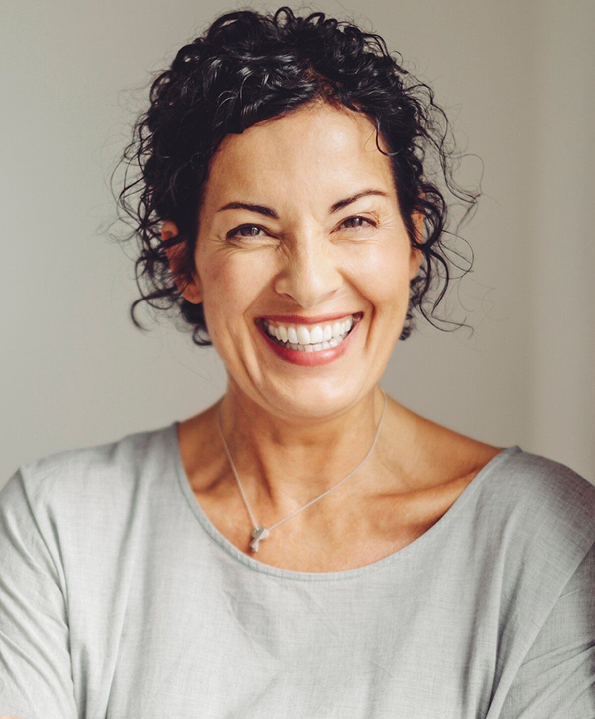 Smiling woman with curly hair in natural light.