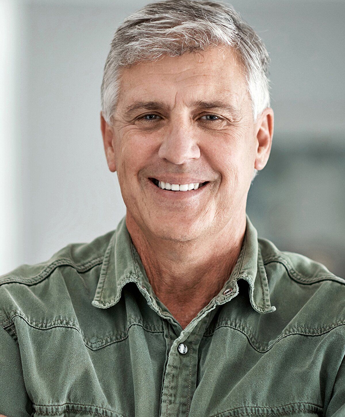 Smiling older man in casual green shirt.