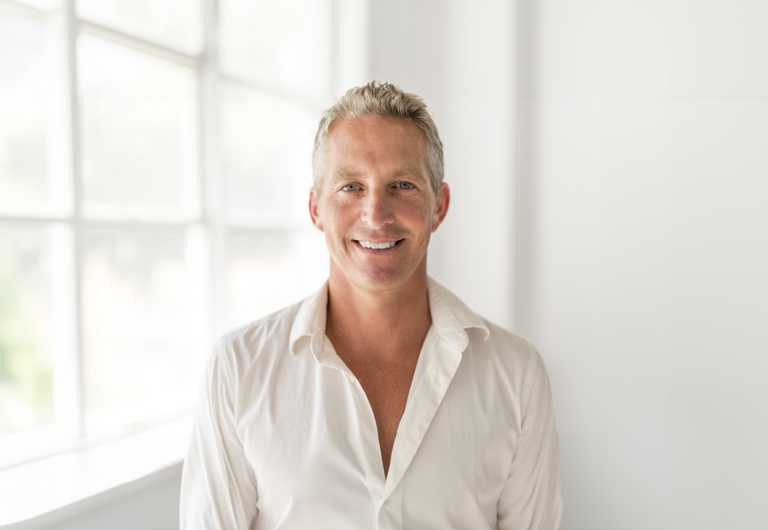 Smiling man in casual white shirt indoors.