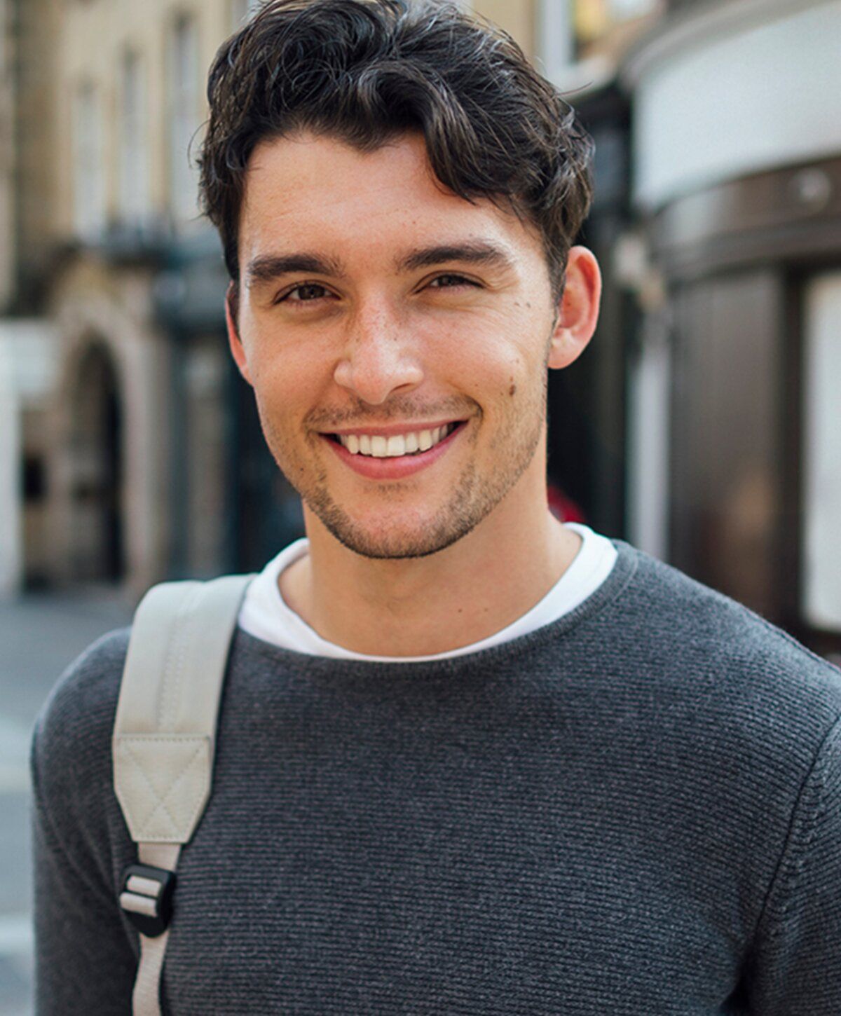 Smiling man in casual sweater outdoors.