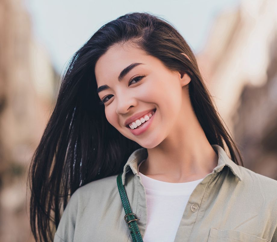 Smiling woman outdoors with long dark hair.