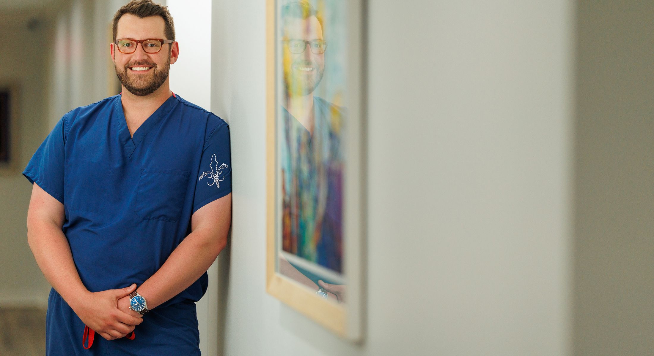Smiling medical professional in blue scrubs.