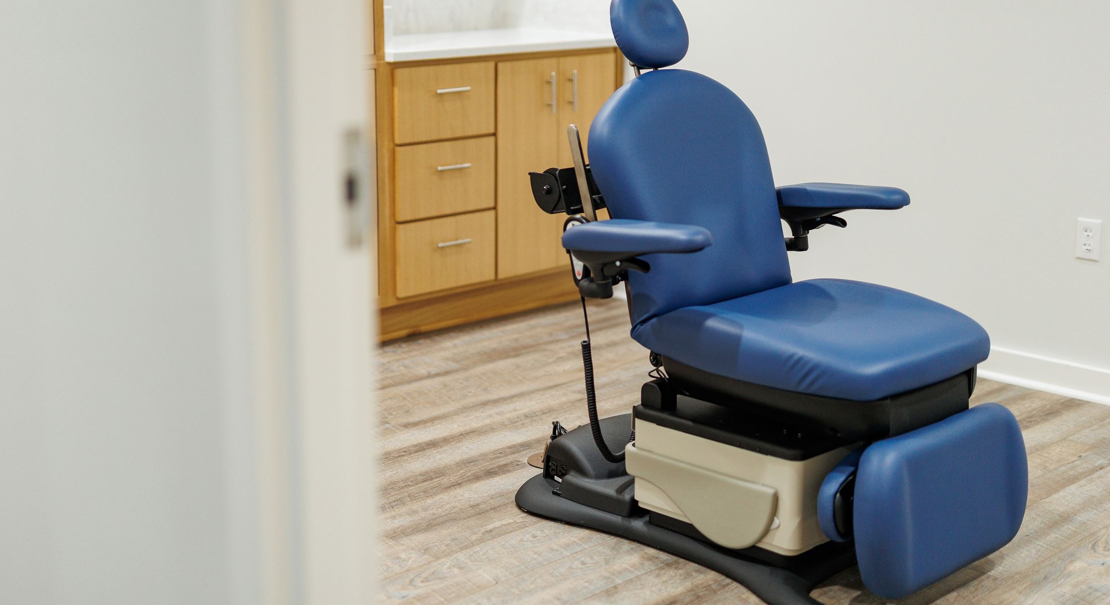 Blue dental chair in a clean clinic room.