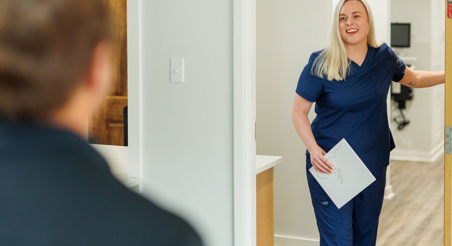Healthcare professional smiling while entering a room.