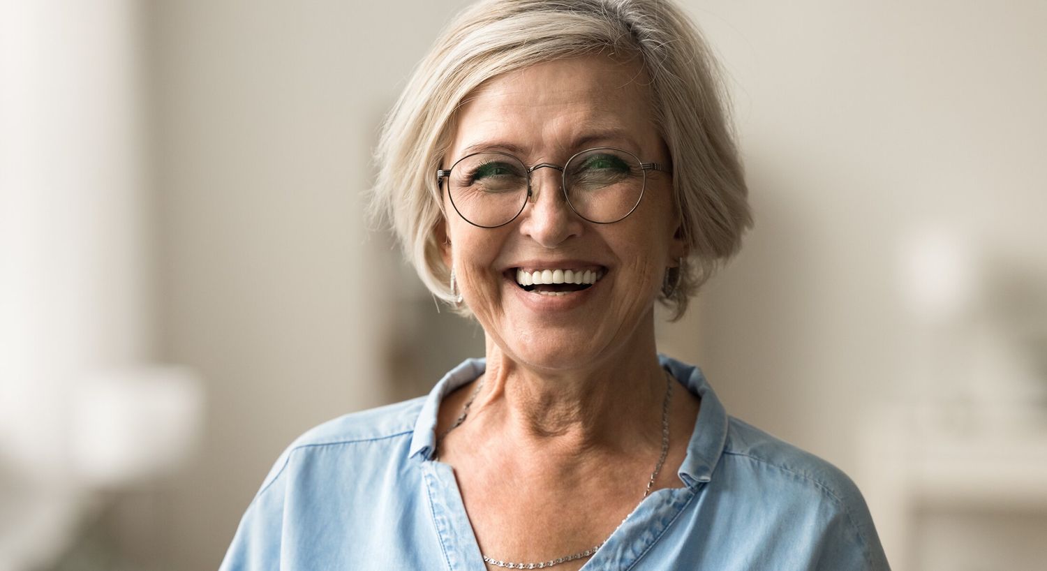 Smiling older woman in casual attire indoors.