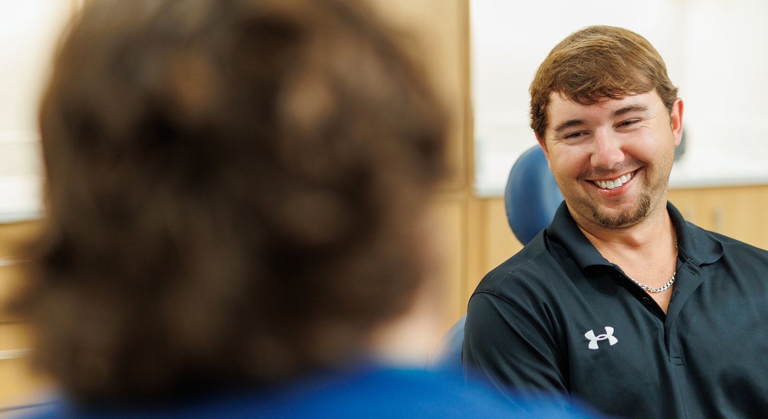 Two men smiling in a conversation indoors.