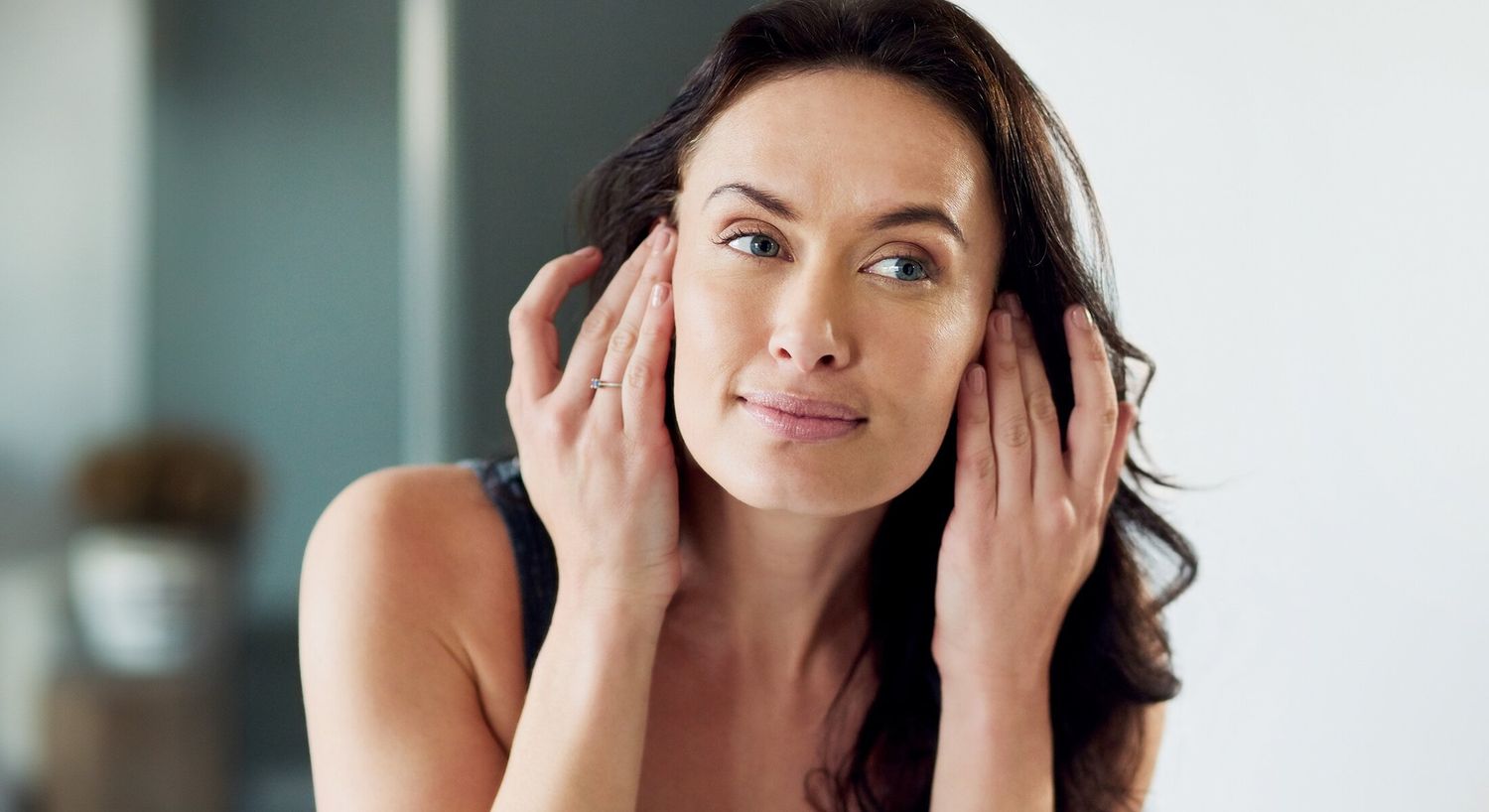 Woman applying skincare in a modern setting.