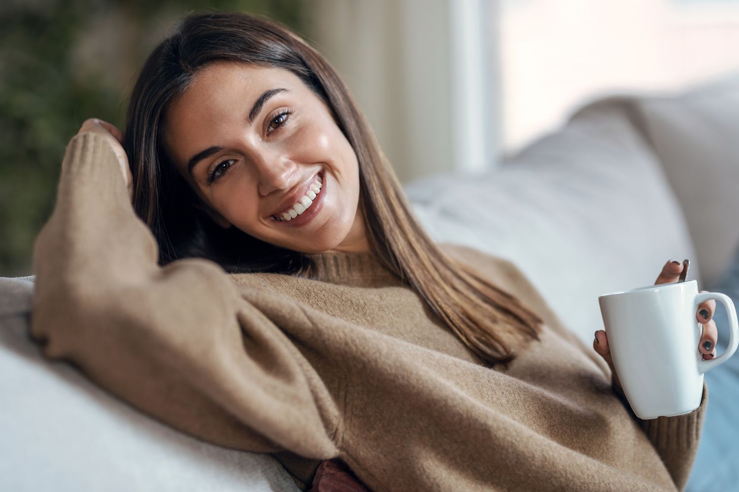 Smiling woman relaxing with a warm drink.