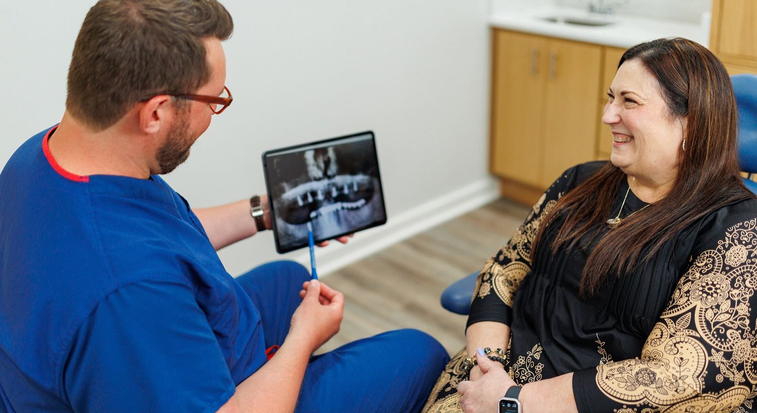 Dentist explaining dental image to smiling patient.